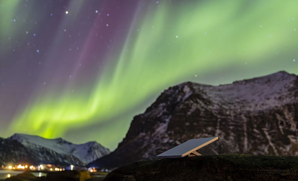 Aurora over snow-dusted peaks with a Starlink Mini set up on the ground