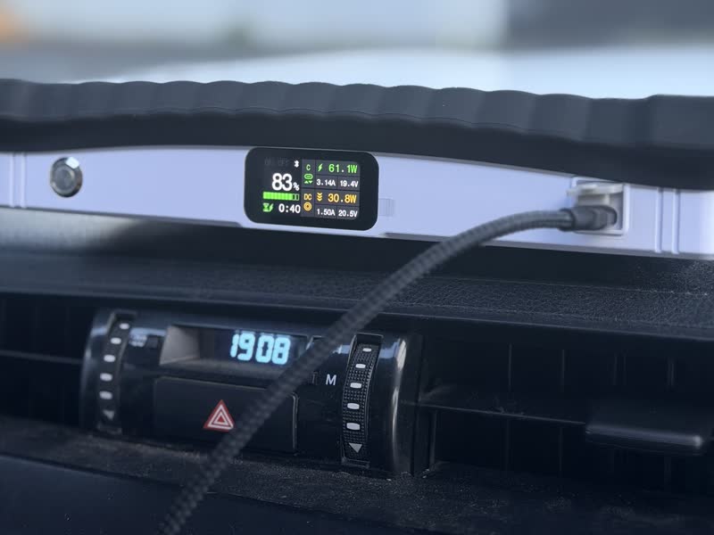 A Starlink Mini lying flat on a car dashboard under the windscreen, its power bank display showing 83% charge
