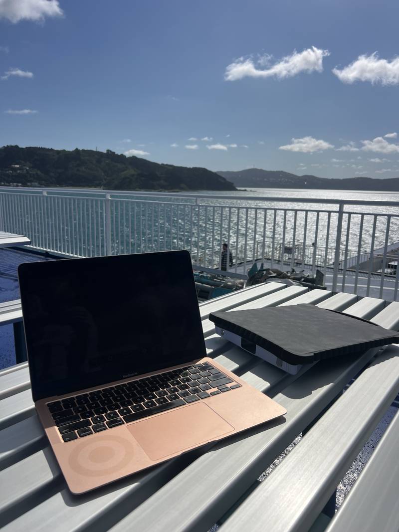 A laptop and a Starlink Mini on a ferry deck table, Queen Charlotte Sound behind