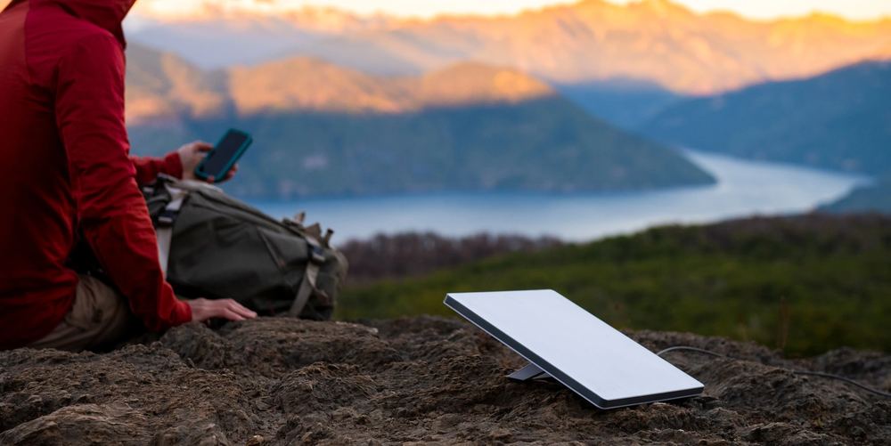 Sitting on a ridge above a lake at sunrise with a Starlink Mini propped on the rock